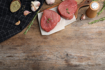 Flat lay composition with fresh beef cut on wooden table. Space for text