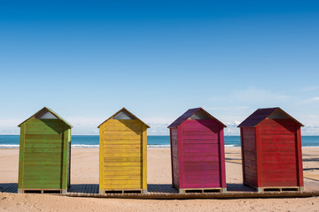 Fototapeta na wymiar Wooden cabins to change clothes on Cullera beach, Valencia, Spain