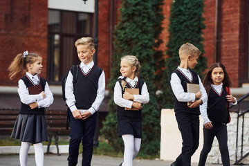 Group of kids in school uniform that is outdoors together near education building