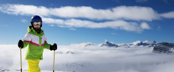Young skier at top of snowy mountains at sun winter day