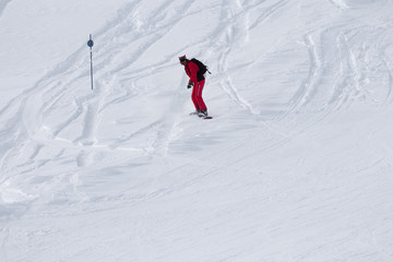 Fototapeta na wymiar Snowboarder in red downhill on snowy off-piste slope