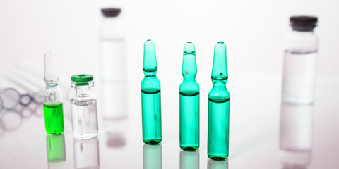 Group of vials with medication on blue methacrylate table.