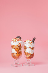 Sweet dessert in glass with biscuit and whipped cream on pink bsckground, selective focus and blank space