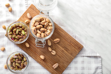 Fototapeta na wymiar Bowls and jar with tasty pistachio nuts on table