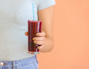 Woman with glass of healthy smoothie on color background, closeup