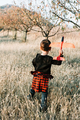 Boy playing with plane toy in the park. Universal children day. Back view