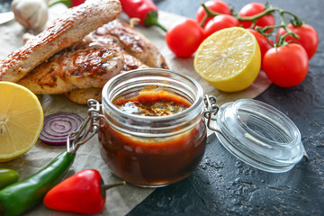 Fototapeta na wymiar Jar of tasty barbecue sauce, chicken, vegetables and spices on table