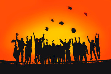 Silhouette of a group of people who jump up and throw a hat showing happiness with success.