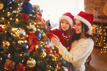 Smiling mom and daughter decorating Christmas tree