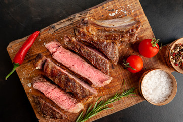 Beef steak, herbs and spices on a cutting board on a background of stone