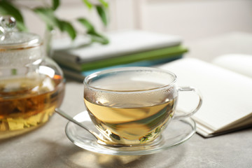 Tasty hot green tea in cup on grey table