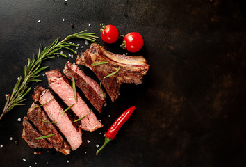 Beef steak, herbs and spices on a stone background, top view