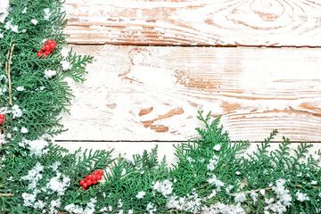 Green coniferous branches with snow on white wooden background