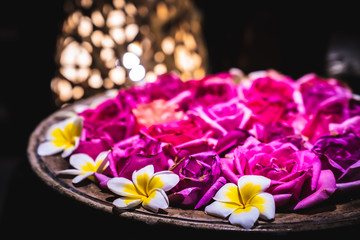 Roses, orchids and plumeria are placed in a terra cotta basin for water to decorate the place.