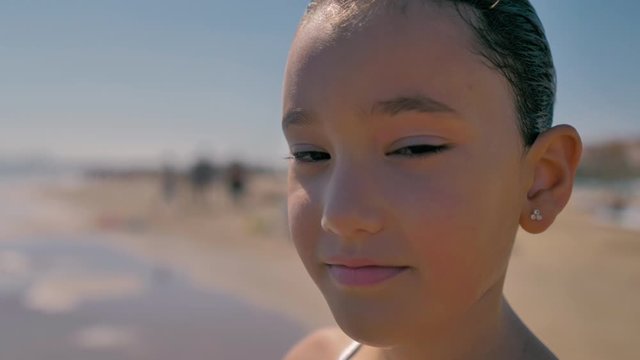primer plano de ni&ntilde;a sonriente con coleta en la playa