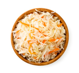 Sauerkraut with carrots in a wooden plate on a white background. The view of top.