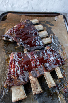 beef short ribs with barbecue sauce on baking tray flat lay