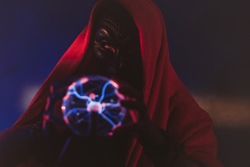 Dark creature is holding in his hands a magic globe with static electricity.