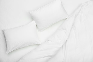 Soft white pillows and blanket on bed, top view