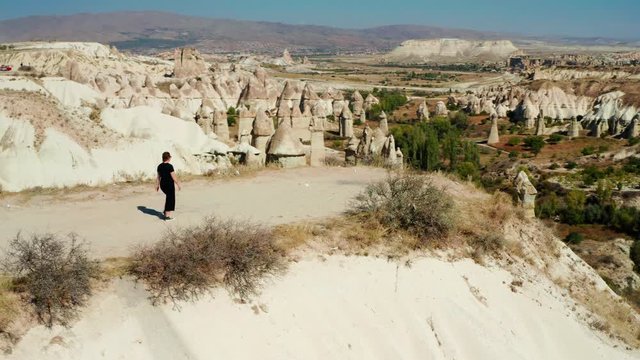 Woman walking towards the edge of a cliff in Love Valley, Cappadocia, Turkey. Aerial left to right pan with woman center frame