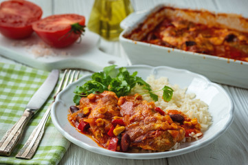Chicken fillet baked in tomato sauce with corn and beans, served with boiled rice. Mexican style cuisine.