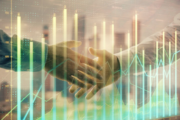 Fototapeta premium Double exposure of financial graph on cityscape background with two businessman handshake. Concept of stock market deal