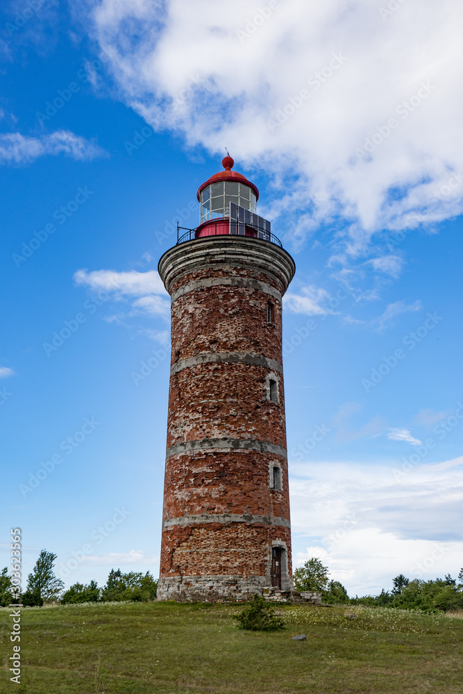 Wall mural Lighthouse and house in the Baltic Sea. Shore, evening light, sunset, clouds and architecture concept. Mohni, small island in Estonia, Europe.