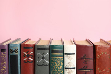 Collection of old books on pink background, space for text