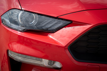 Fototapeta na wymiar Metallic red surface details of the headlights of a luxury sports car