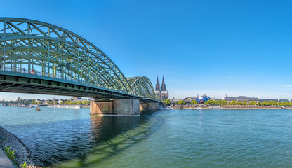 Obraz premium Panorama of the Hohenzollern bridge over Rhine river on a sunny day. Beautiful cityscape of Cologne, Germany with cathedral and Great St. Martin Church in the background