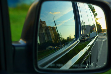 the body of the minibus reflected in the side mirror of the car