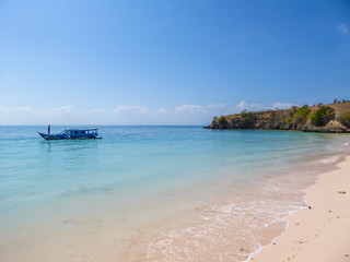 Fototapeta na wymiar A peaceful Pink Beach in Lombok, Indonesia. Some boats are placed on the shore, others are drifting on a calm surface of the sea. Hidden gem of Indonesia, unspoiled place by humans. Relaxation