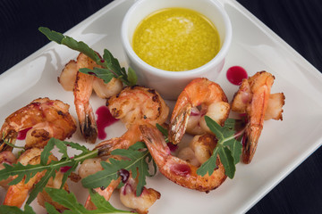 Fried shrimps with sauce and arugula on plate