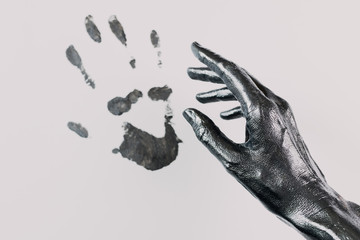 Handprint on light paper. The hand is painted black with a metallic sheen. Minimalism.