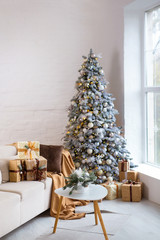 Fototapeta na wymiar Interior of bright modern living room with comfortable sofa decorated with Christmas tree and gifts