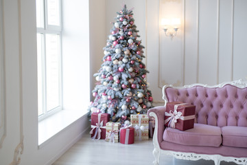 Interior of bright modern living room with comfortable sofa decorated with Christmas tree and gifts