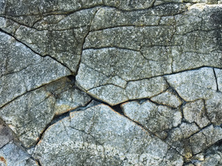 Abstract background. Rough cracked stone wall, cracks closeup