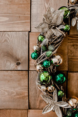 Festive wreath made of rattan and twigs handmade made, decorated with christmas toys on wooden background. Christmas, New Year composition