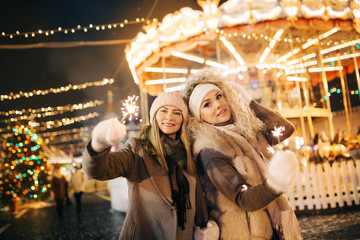 Photo of two women on background of carousel in park