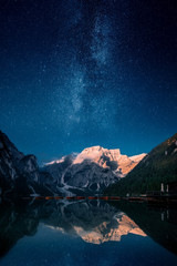 Beautiful first light on a mountain top against stars and milky way in Lago Di Praies, Dolomites,...