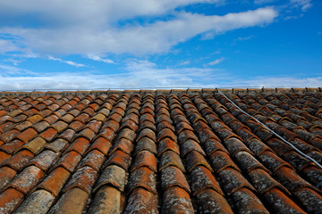 old clay tile roof against blue sky