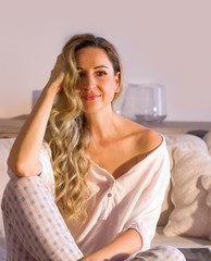 Naklejka premium Woman sitting on the sofa, touches her smiling hair and enjoys the morning