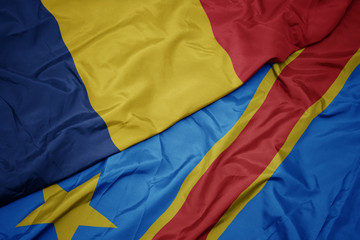 waving colorful flag of democratic republic of the congo and national flag of romania.