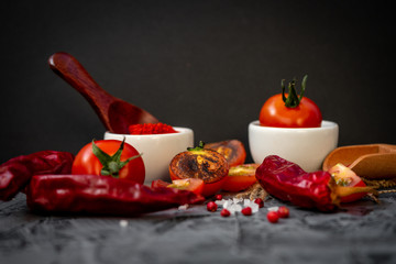 Grilled cherry tomatoes, red pepper, salt and spices on black background