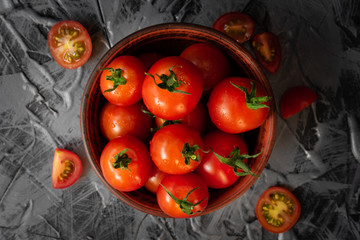 Ripe red tomatoes with green sprigs in a clay Cup on a concrete table top view