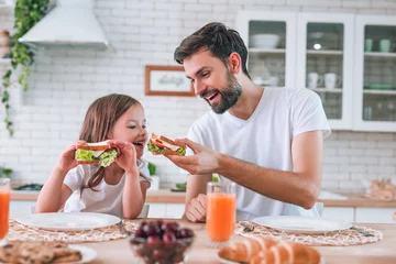 Papier Peint photo Lavable Snack papa nourrissant une fille mangeant avec son sandwich pour le petit déjeuner dans la cuisine