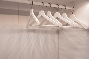 Many wooden white hangers on a rod. Store concept, sale, design, empty hanger. Relocation, divorce, new housing, change of residence