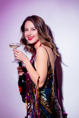 Beautiful woman with serpentine and champagne in a New Year time. Shot with flash.