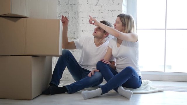 Young happy millennial couple students move into their first new owners home. Simple white background of urban apartment, they frame and decide on decoration on walls