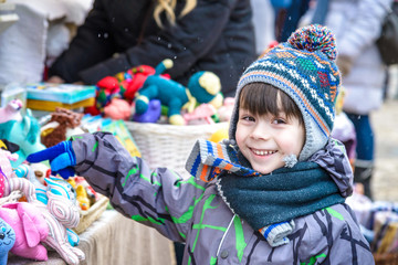 Little cute kid boy selecting decoration on Christmas market. Beautiful child shopping for toys and decorative ornaments. Traditional winter holiday event